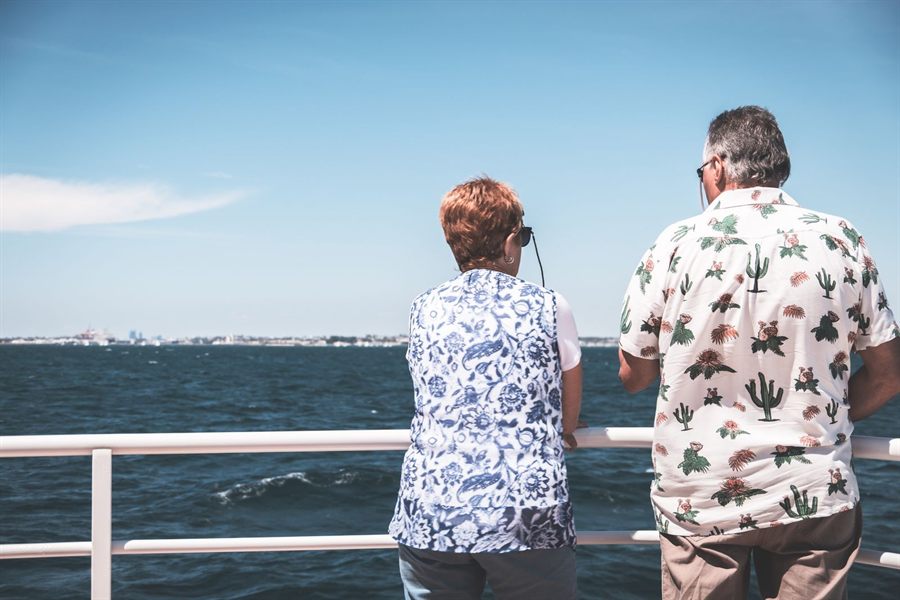 Couple at the rail of a ship deck looking out to sea